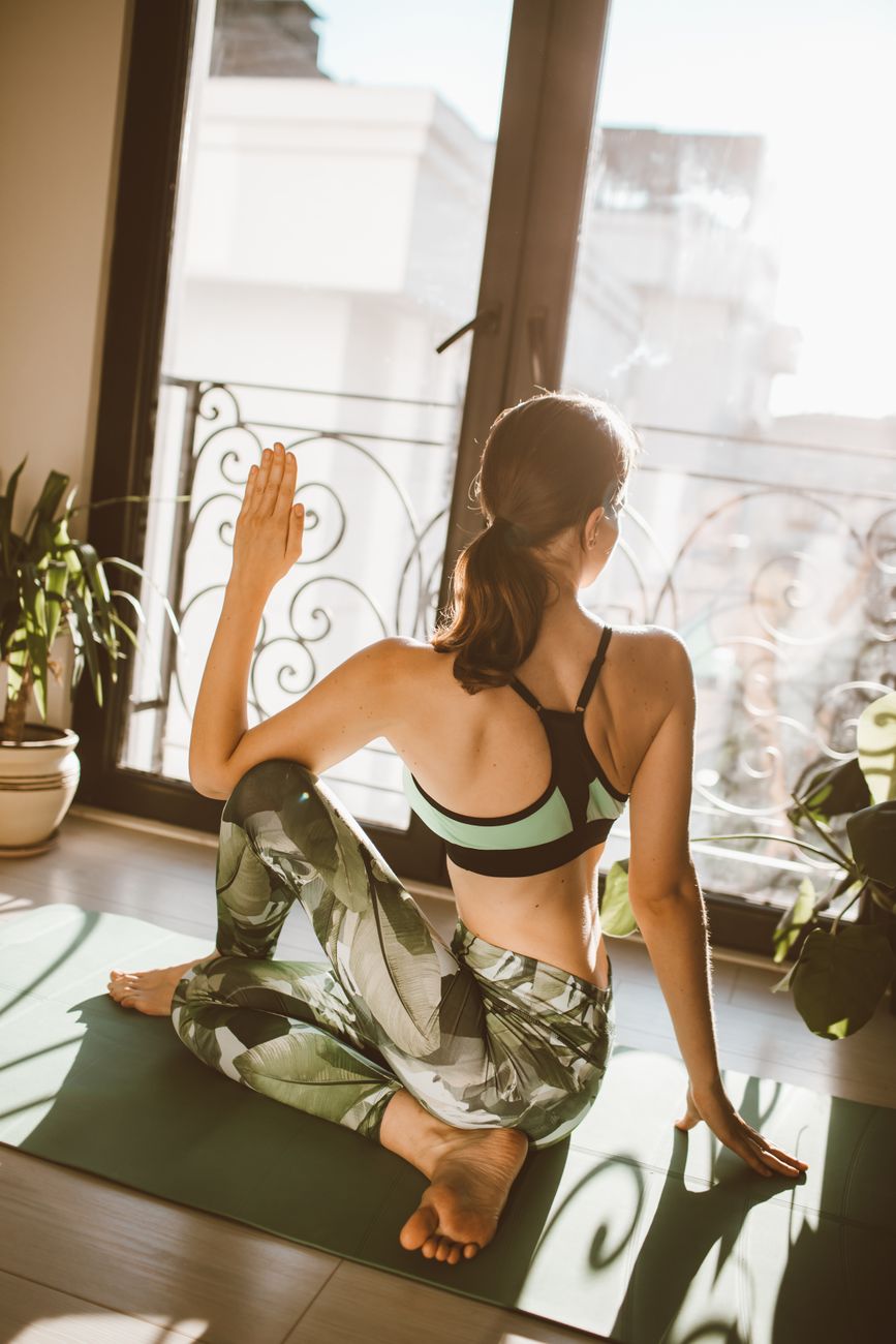 Mujer practicando yoga en casa con luz natural